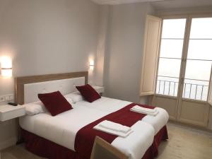 1 dormitorio con 1 cama grande con almohadas rojas y blancas en Apartamentos Pinar Malaga Centro, en Málaga