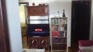 a living room with a tv and a book shelf at Aconchego dos schreiber in Belo Horizonte