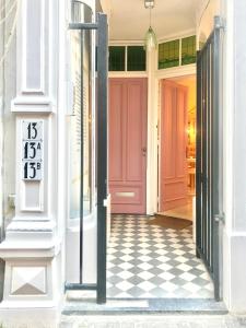 una puerta rosa en un edificio blanco con suelo a cuadros en The Sunny Suite - R.Q.C. en The Hague