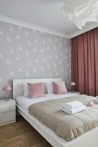 1 dormitorio con 1 cama blanca grande con almohadas rosas en Metro Imielin Apartments, en Varsovia