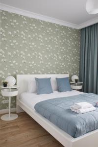 a bedroom with a white bed and a floral wall at Metro Imielin Apartments in Warsaw