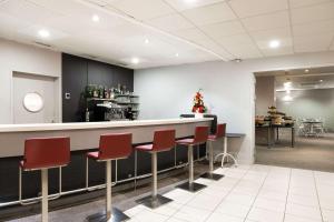 a bar in a waiting room with red chairs at Quality Hotel Pau Centre Bosquet in Pau