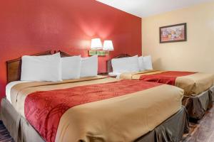 Dos camas en una habitación de hotel con paredes rojas. en Rodeway Inn, en Jeffersonville