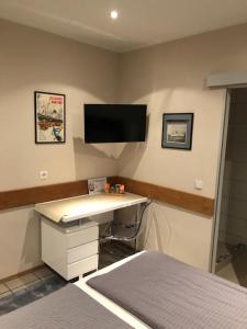 Schlafzimmer mit einem Schreibtisch und einem TV an der Wand in der Unterkunft Hotel zum Schiffchen in Brüggen