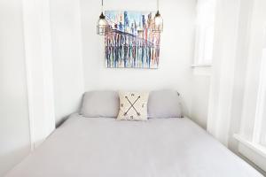 a bed in a white room with a picture on the wall at The 1920s Mainstay Studio Flat on Lower Greenville in Dallas