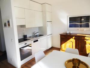 a white kitchen with white cabinets and a table at Casa Marco in Brione