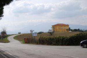 a road leading to a yellow house on a hill at Residence Borgo Offida in Offida