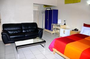 um quarto com uma cama e um sofá de couro preto em Hôtel Saint Thomas em Lomé