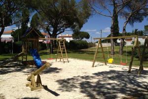 um parque infantil com um baloiço e uma estrutura de jogos em Buganvília Apartment Praia da Falésia em Albufeira