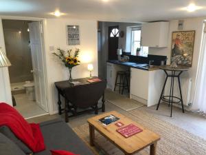 een woonkamer met een bank en een keuken bij Kristina's Coach House in Horsham