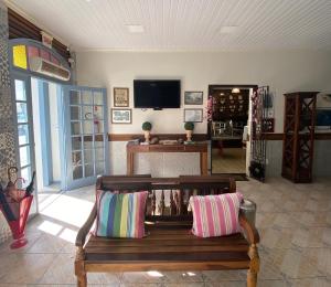 a living room with a bench and a tv at Hotel Rota Do Mar Inn Itajaí Navegantes in Itajaí