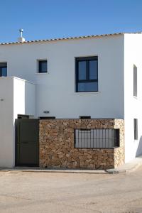 a white house with a stone wall and a garage at Alojamiento rural La Moravieta in Pozoamargo +33 photos