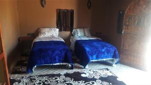 two beds with blue covers sitting in a room at Mhamid Auberge Saharaespace in Mhamid