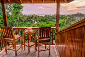 a porch with two chairs and a table with flowers on it at Seaside Inn Roatan in West Bay