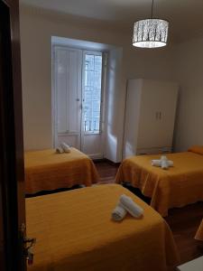 a room with three beds with orange sheets at Pensión Hedrass in Santiago de Compostela