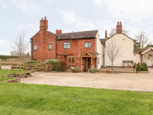 an old red brick house with a fence and grass at Bellamour End Cottage in Rugeley