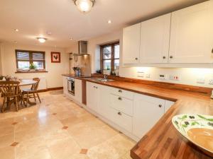 a large kitchen with white cabinets and a table at Bellamour End Cottage in Rugeley