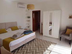 1 dormitorio con 1 cama con silla y espejo en Casa de Sabine, en Olhão