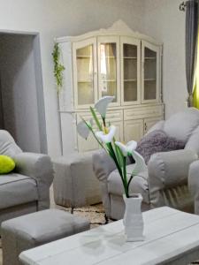 una sala de estar con sofás y un jarrón con flores en Appart meublé le Dakota, en Yaoundé