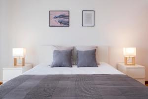 um quarto com uma cama com almofadas azuis e 2 candeeiros em Paim Apartments em Ponta Delgada