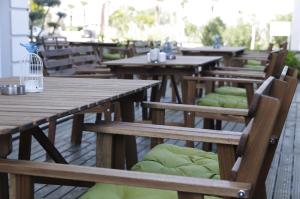 a row of wooden tables and chairs with green cushions at Urla Zeytin Hotel in Urla