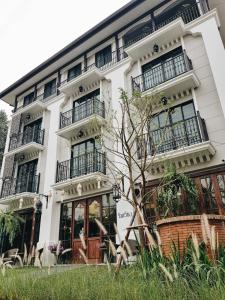 - un bâtiment blanc avec des balcons et un arbre en face dans l'établissement Rimwiang, à Chiang Mai