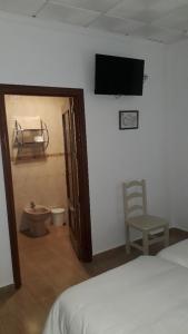 sypialnia z łóżkiem, telewizorem i krzesłem w obiekcie Hostal VILLA CARBULA w mieście Almodóvar del Río