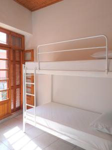 Litera blanca en habitación con ventana en Backpackers & Travelers Central old town en Ioánina