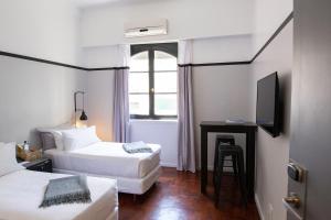 una camera d'albergo con due letti e una scrivania con televisore di Carsson Hotel Downtown Buenos Aires a Buenos Aires