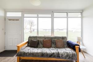 a couch in a living room with a large window at The Beach Huts - Camber Sands in Camber +65 photos