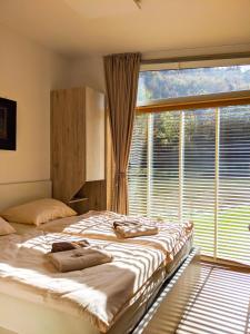a bedroom with two beds and a large window at Naturasort Holiday Houses in Pesnica pri Mariboru