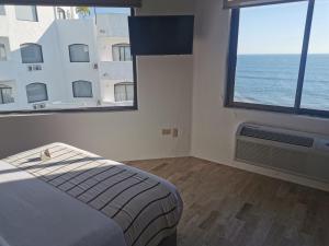 a bedroom with a bed and two large windows at Gaviana Resort in Mazatlán