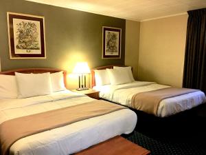 a hotel room with two beds and a lamp at Scottish Inns Fayetteville in Fayetteville +10 photos