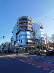 un gran edificio de cristal en una calle de la ciudad con coches en Prince III, en Novi Sad