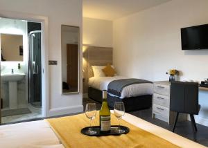 um quarto de hotel com uma cama e dois copos de vinho em McNaughton Guestrooms em Ballymena