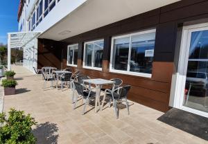 eine Terrasse mit Tischen und Stühlen neben einem Gebäude in der Unterkunft Hotel Prados in Lugo