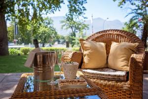 a wicker chair and table with a bottle of wine at Oak Tree Lodge in Paarl