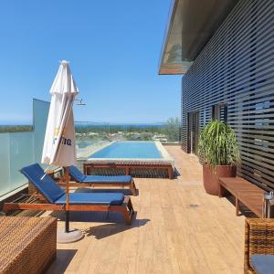 um pátio com cadeiras, um guarda-sol e uma piscina em Vogue Square Fashion Hotel by Lenny Niemeyer no Rio de Janeiro