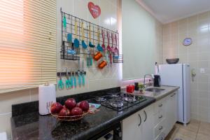 a kitchen with a stove and a bowl of apples on the counter at APÊ 5 ESTRELAS CENTRAL-FREE VAGA&NETFLIX in Ribeirão Preto