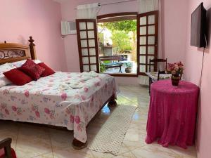 1 dormitorio con cama, mesa y TV en Cantinho da tia Lira, en Cabo Frío