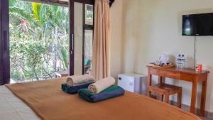 a bedroom with a bed with a desk and a window at Salili Bungalow in Gili Air
