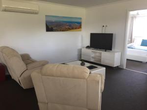 a living room with a couch and a television at Macquarie Barracks Motor Inn in Port Macquarie