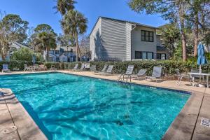 a swimming pool with chairs and a house at Coastal Oasis with Pool - Walk to Coligny Beach Park in Hilton Head Island