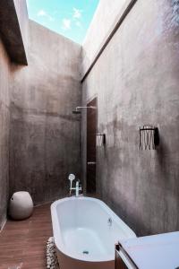 a bathroom with a white tub and a concrete wall at Charlie's El Nido Managed by HII in El Nido