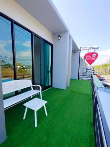 una habitación con césped verde y un banco en el balcón en Belong Boutique Luxury Hotel, en Ban Wang Khon