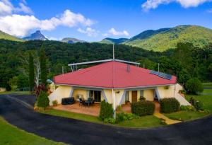 ein Haus mit rotem Dach mit Bergen im Hintergrund in der Unterkunft A view of Mount Warning in Uki