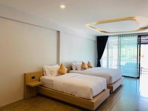 two beds in a room with white walls at Belong Boutique Luxury Hotel in Ban Wang Khon
