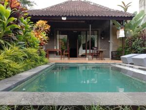 a swimming pool in front of a house at Dedik House in Ubud