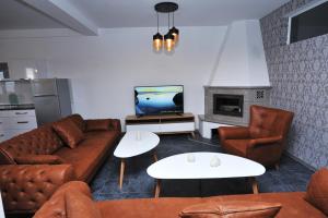 ein Wohnzimmer mit einem Sofa, Stühlen und einem TV in der Unterkunft Lagadin Lakeview Apartment in Ohrid