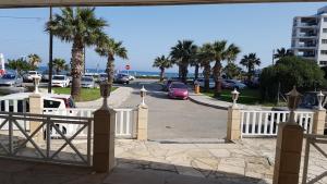 a white fence with palm trees and a parking lot at ZORBAS Sea View No 5 in Larnaka